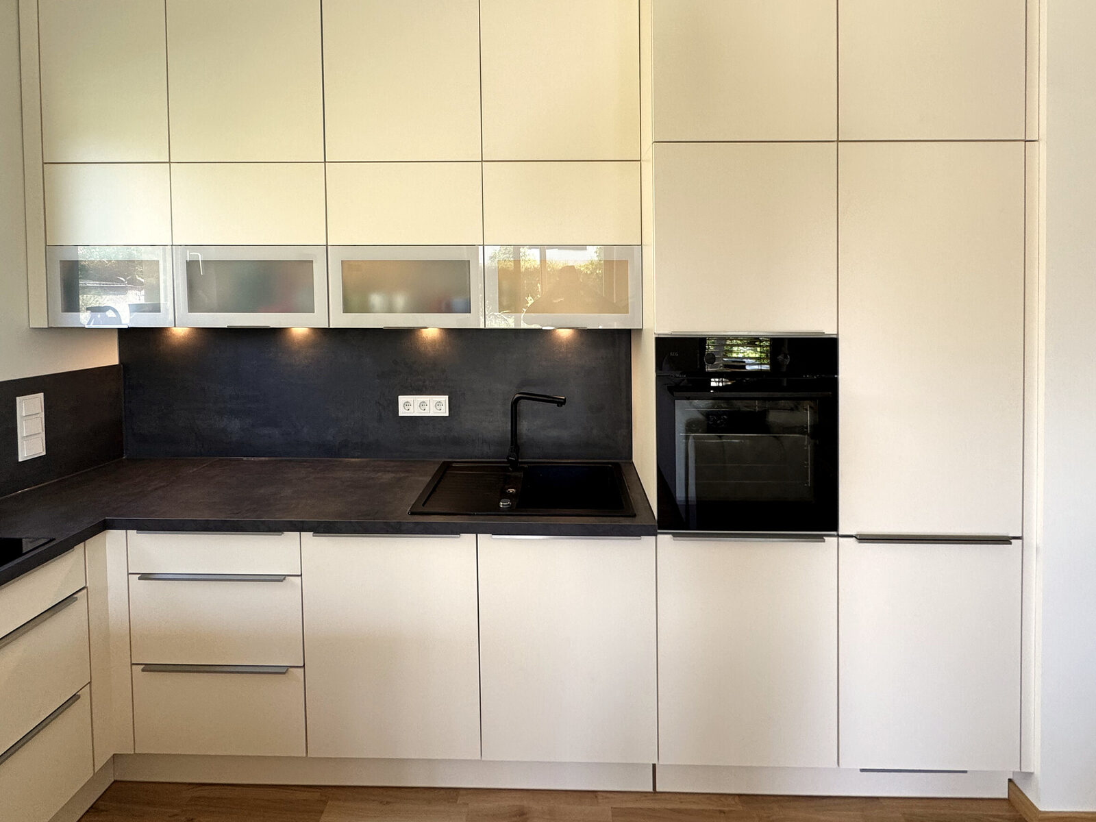 Einbauküche in einer vermieteten Neubauwohnung: weiße Fronten, dunkle Arbeitsplatte, Einbaubackofen