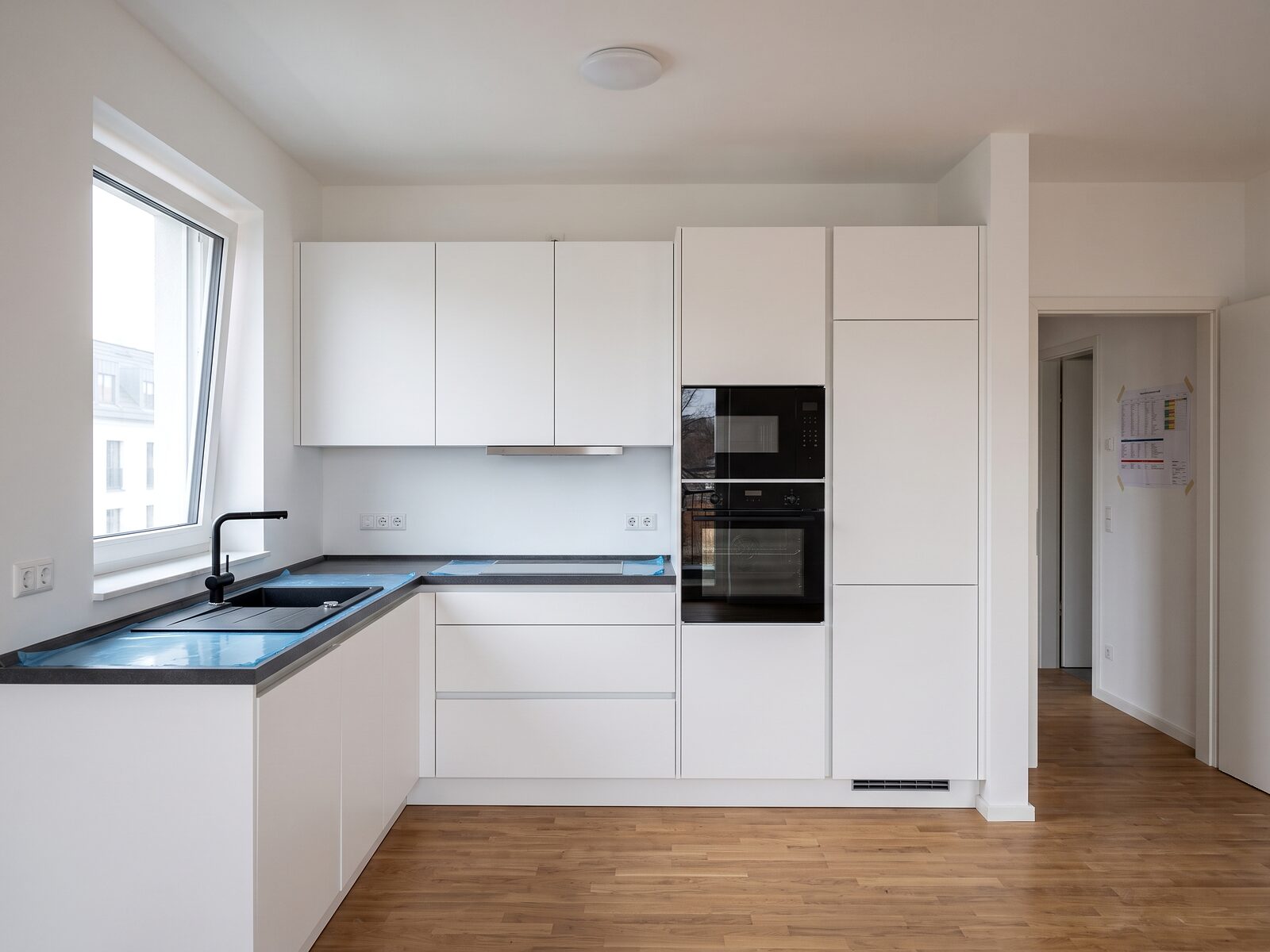 Frisch montierte Küche in einer unmöblierten Neubauwohnung, Schutzfolie noch auf der Arbeitsplatte